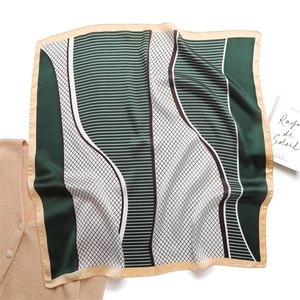 Detailed flat lay of a dark green geometric silk scarf with intricate grid patterns