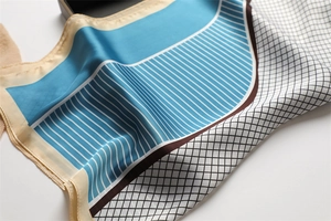 Close-up of geometric pattern silk scarf with blue and white stripes and hemmed edges