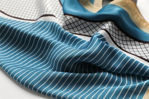 Close-up of silk-textured square scarf featuring geometric stripes and grid patterns