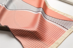 Macro view of geometric silk scarf showing orange and beige wavy patterns and satin texture