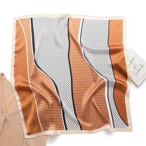 Detail of geometric pattern silk scarf with orange and black color blocks on knitwear