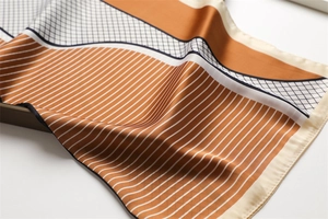 Detailed shot of silk scarf fabric showing orange stripes and black grid patterns