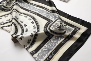 Vista dettagliata del foulard in seta con motivi di carrozze vintage e volute barocche