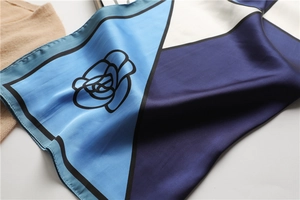 Detailed view of the smooth silk texture and geometric camellia pattern on the blue scarf