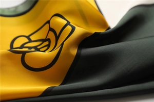 Detailed macro view of silky satin scarf with elegant yellow and green floral patterns