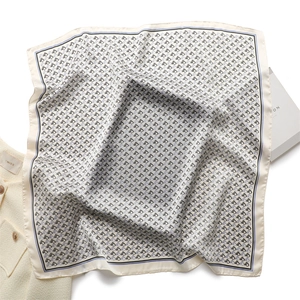 Detailed view of cream silk scarf with horse head print on elegant white coat background