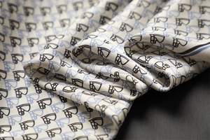 Detailed view of silk square scarf featuring equestrian horse bit print and glossy texture
