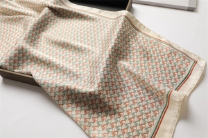 Detail of silk scarf showing orange and green horse head print and elegant satin texture