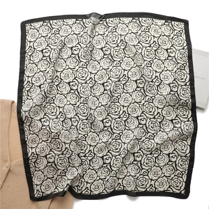 Detailed close-up of a square silk scarf with black and white rose floral patterns