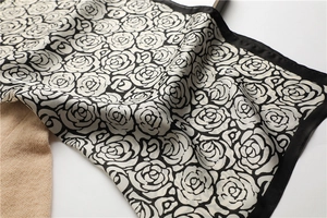 Close-up of silk scarf with black and white camellia print on brown knitwear