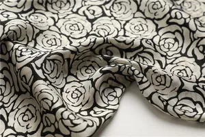 Detail of silk-like scarf featuring elegant black and white rose floral print patterns