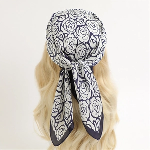 Elegant white square silk scarf with navy rose print tied on golden blonde hair