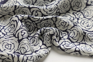 Detail of white silk scarf with navy blue camellia floral pattern and smooth texture