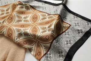 Détail d'un foulard en soie vintage avec volutes dorées et motifs floraux géométriques
