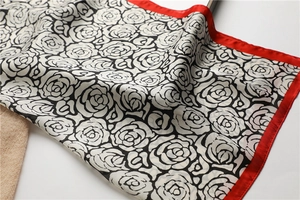 Detailed texture of camellia floral silk scarf with vibrant red borders and satin finish