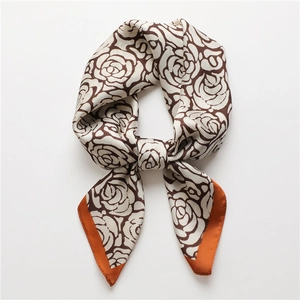 Detail of silk square scarf featuring dark brown rose pattern and orange stitched edges