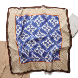 Détail d'un foulard en soie vintage aux motifs floraux géométriques et bordures orangées