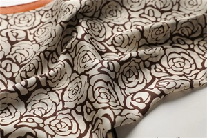 Macro detail of silk scarf featuring retro brown rose floral patterns on cream fabric
