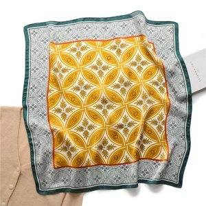 Détail d'un foulard en soie à motif floral à quatre feuilles et design géométrique jaune
