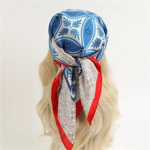 Détail du foulard en soie à motif feuille rouge, bleu et blanc noué sur la tête