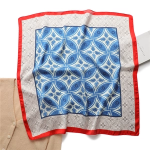 Détail à plat d'un foulard en soie vintage aux motifs bleus et bordure rouge vif