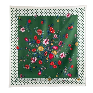 Detailed close-up of dark green floral silk scarf with polka dot borders and smooth texture