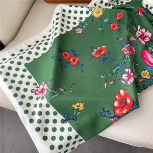 Detail of green silk scarf with tropical floral print and large white polka dots