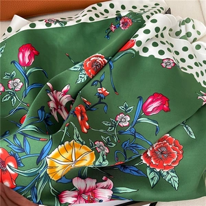 Detailed texture of silk scarf with floral print, polka dots, and green edge finish