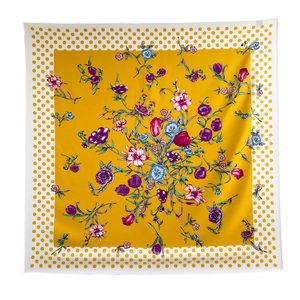 Detailed close-up of silk scarf showing vibrant floral patterns and yellow polka dot borders