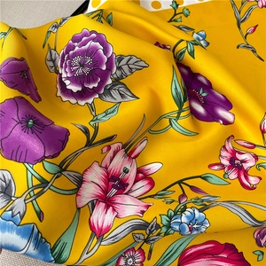 Close-up of yellow silk scarf featuring colorful floral patterns and twill weave texture