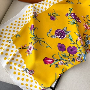 Detail of yellow floral silk scarf with polka dot borders on a soft textured sofa