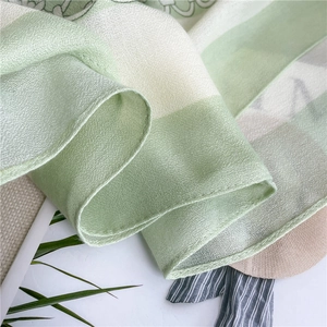 Close-up of light green floral print scarf with refined rolled edges and breathable fabric
