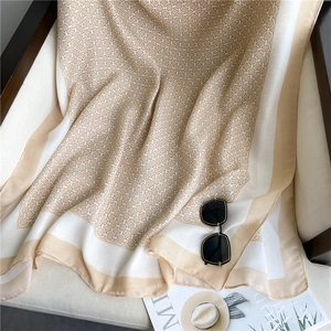 Detail of elegant chain pattern scarf draped on a chair with stylish sunglasses