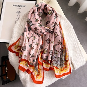 Detailed close-up of a pink floral cotton linen scarf with geometric patterns and feathers
