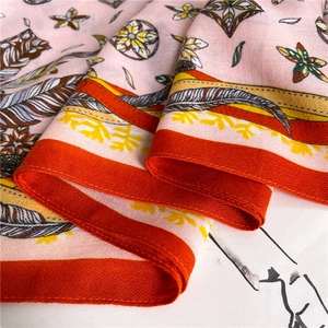 Detail view of pink cotton linen scarf with elegant feather floral prints and orange stitching