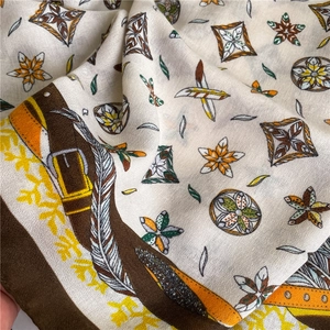Close-up of ethnic print scarf with feather and mandala patterns on silk-like fabric