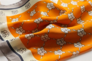 Detailed view of silk scarf fabric showing the H logo pattern and hand-rolled edges