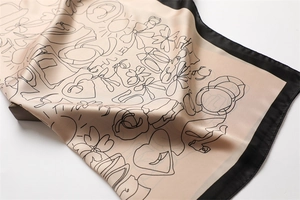 Detail of elegant champagne silk scarf with hand-drawn floral patterns and black borders