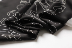 Macro shot of luxury black silk scarf with white abstract line patterns and silky texture
