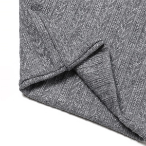 Vue détaillée du tricot gris avec motif de torsades et texture verticale épaisse