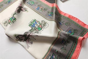 Close-up of luxury silk scarf showing intricate carriage patterns and soft pink borders