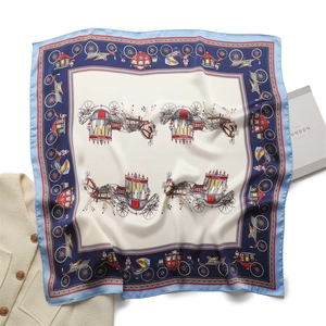 Detailed close-up of luxury silk scarf featuring carriage prints and navy blue border
