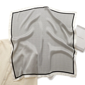 Detail shot of a black and white checkered silk scarf with a wide black border finish