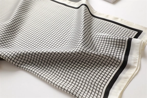 Detailed view of the smooth satin texture and elegant black grid pattern on the square scarf