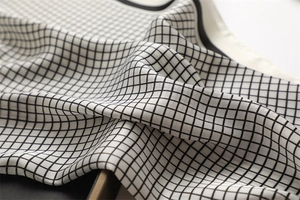 Detail of silk scarf showing black and white checkered pattern and smooth texture