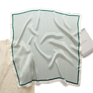 Flat lay of a green checkered square scarf with silk texture next to a London prop book
