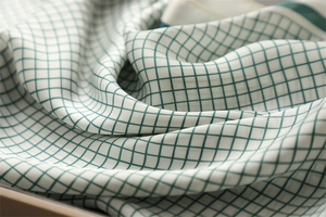 Close-up of green checkered silk scarf texture with soft light and smooth finish
