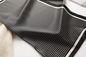 Detailed view of black and white checkered silk scarf texture and elegant hemmed edges