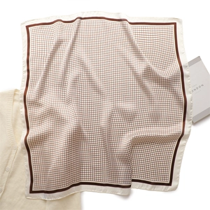 Detail of silk-like square scarf with retro check pattern and dark brown border edge