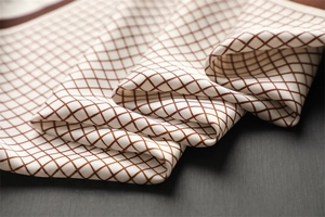 Detailed texture of checkerboard pattern silk scarf with fine stitching on fabric edges